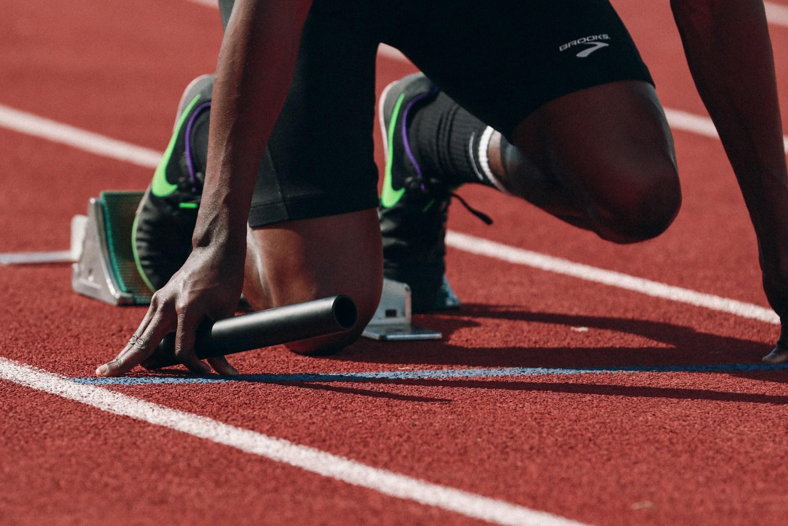 Close-up of a relay runner holding a baton at the starting blocks